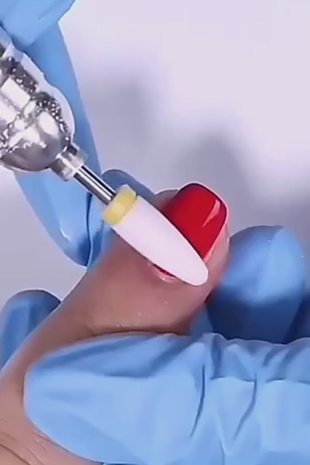 vidéo d'utilisation d'un embout céramique ponceuse ongle sur un ongle vernis rouge